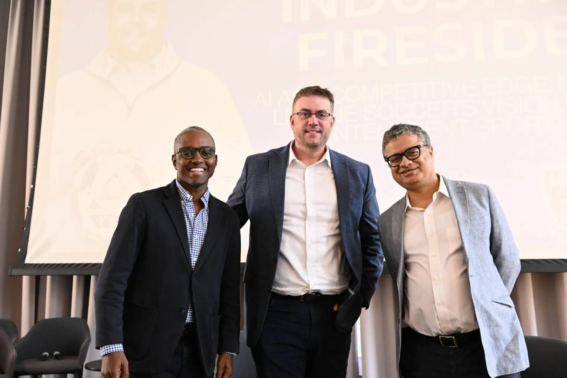 3 panelists smiling for a group photo in front of a faded graphic 