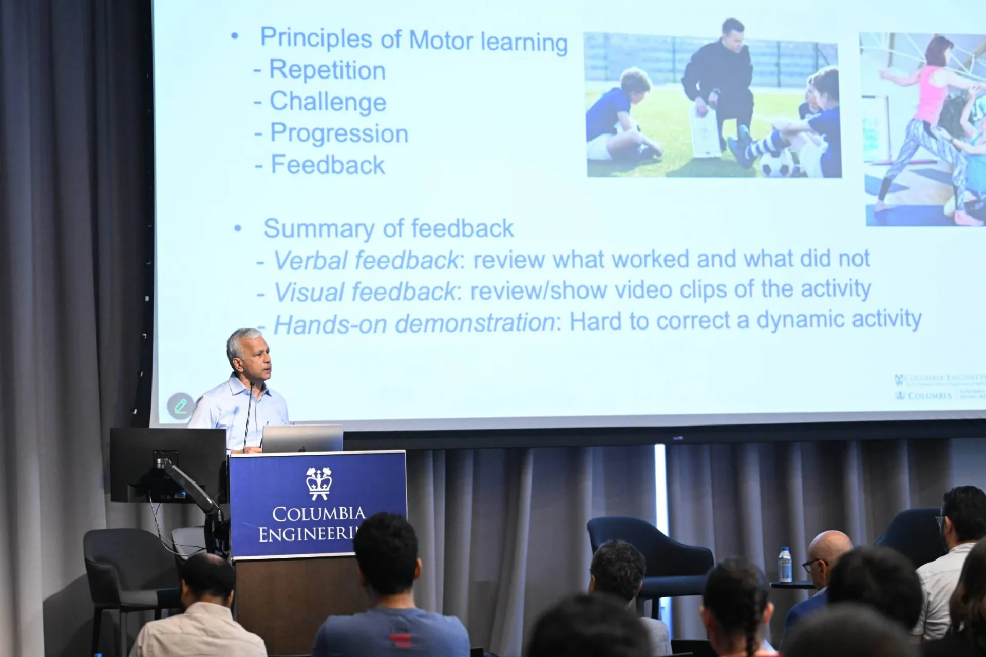 speaker at the podium, delivering presentation with a slide deck that describes the "principles of motor learning"