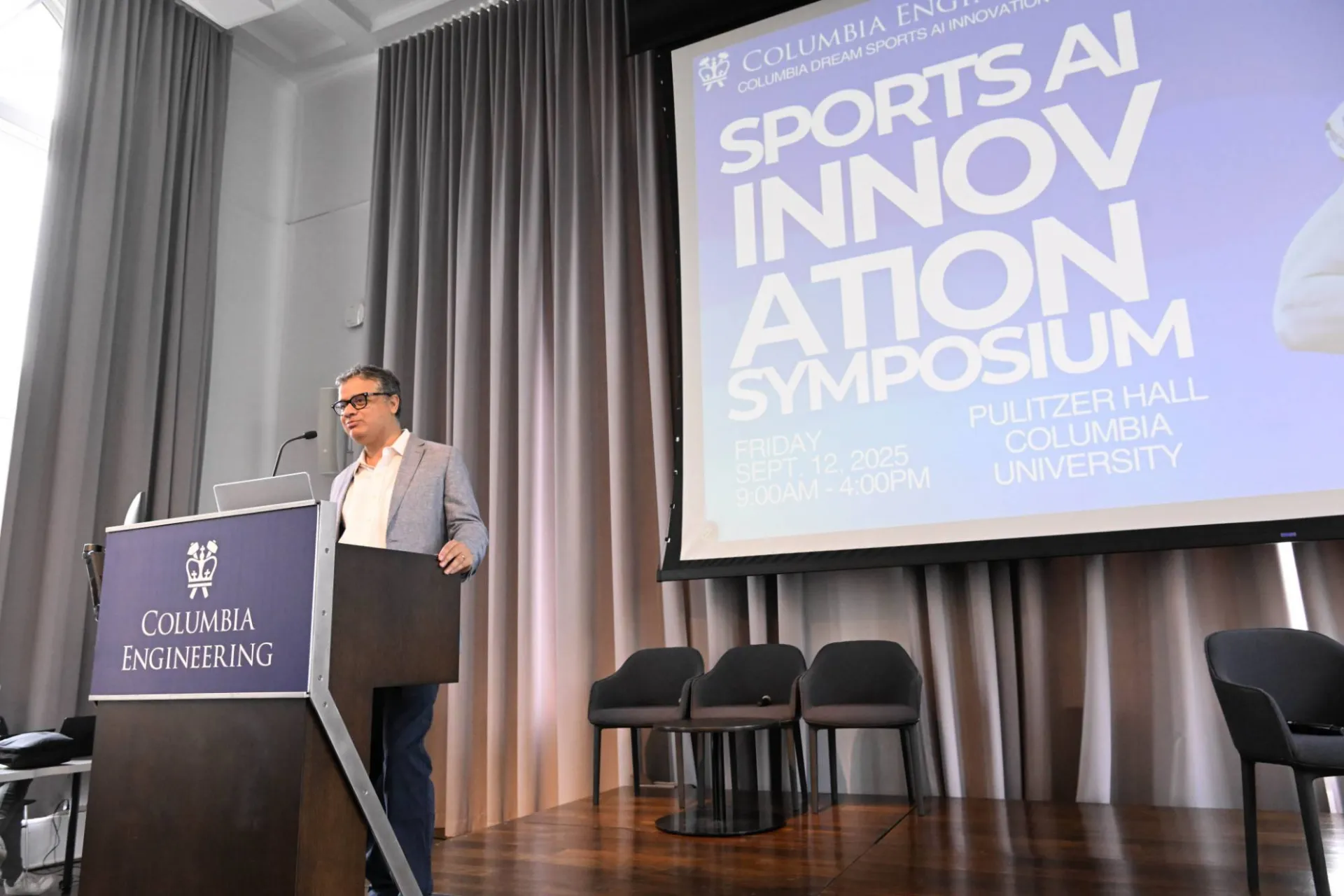 photo of a speaker at the podium, with a "Sports AI Innovation Symposium" graphic displayed behind