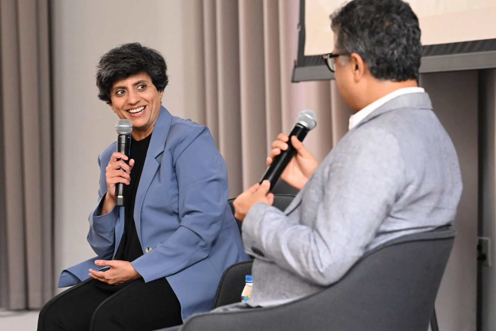 image of 2 panelists speaking to each other, one facing away from the camera