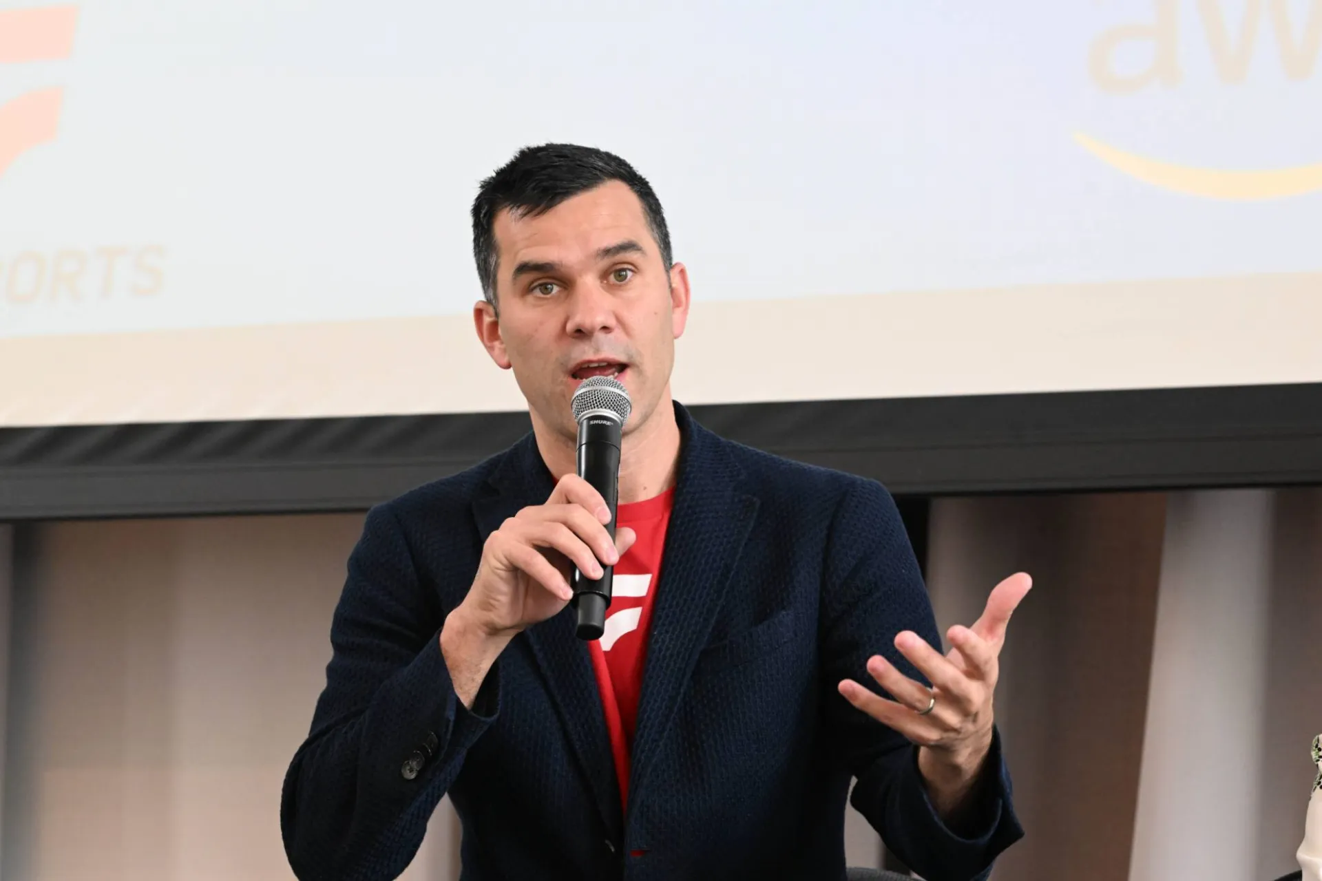 image of a speaker holding a microphone addressing an audience