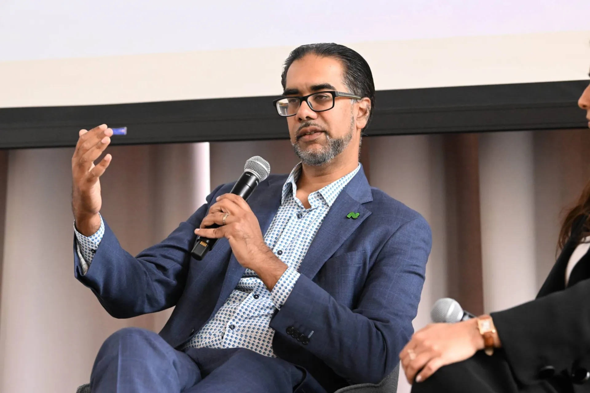 close up shot of man in a suit speaking to an audience with a microphone
